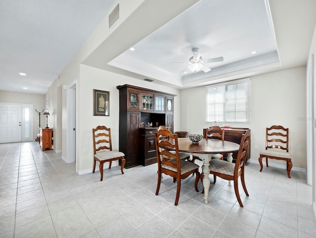 tiled dining space featuring a raised ceiling and ceiling fan