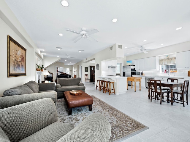 tiled living room with ceiling fan and sink