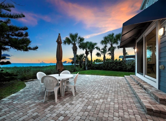 patio terrace at dusk featuring a water view