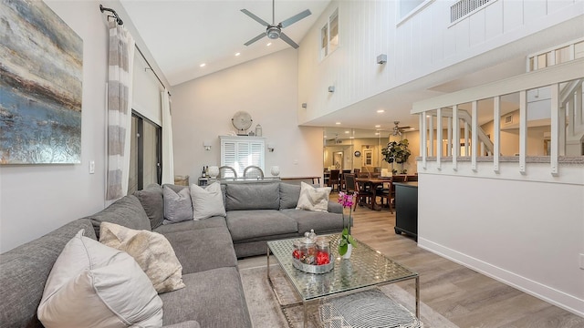 living room featuring hardwood / wood-style flooring, ceiling fan, and high vaulted ceiling