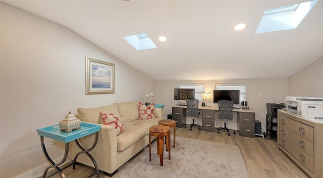 office area with light hardwood / wood-style floors and vaulted ceiling with skylight