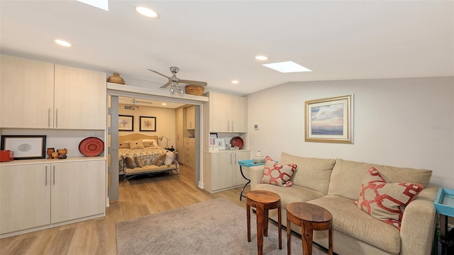 living room with ceiling fan, lofted ceiling with skylight, and light hardwood / wood-style flooring