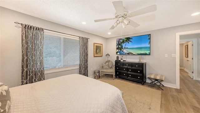 bedroom with a textured ceiling, light hardwood / wood-style floors, and ceiling fan