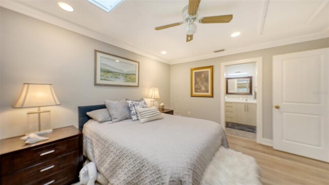 bedroom with ensuite bathroom, a skylight, light hardwood / wood-style flooring, ceiling fan, and ornamental molding