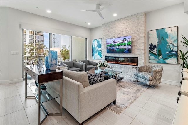 living room with light tile patterned floors, a stone fireplace, and ceiling fan