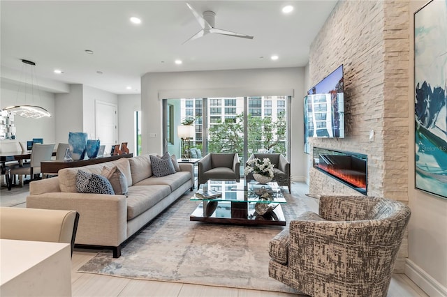 living room with a stone fireplace and ceiling fan