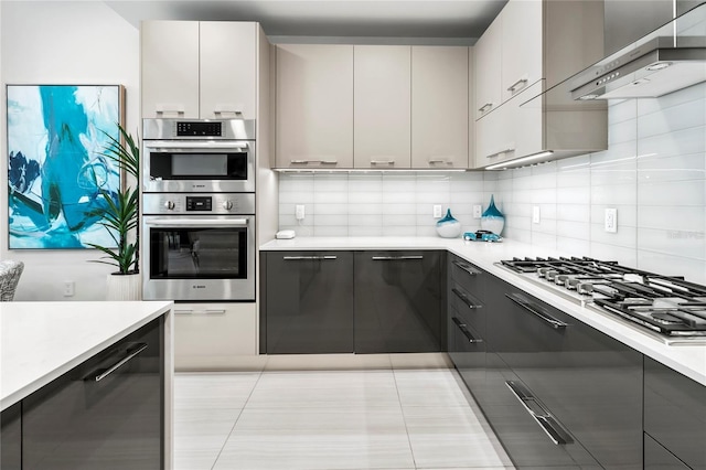 kitchen with white cabinetry, wall chimney range hood, decorative backsplash, and stainless steel appliances