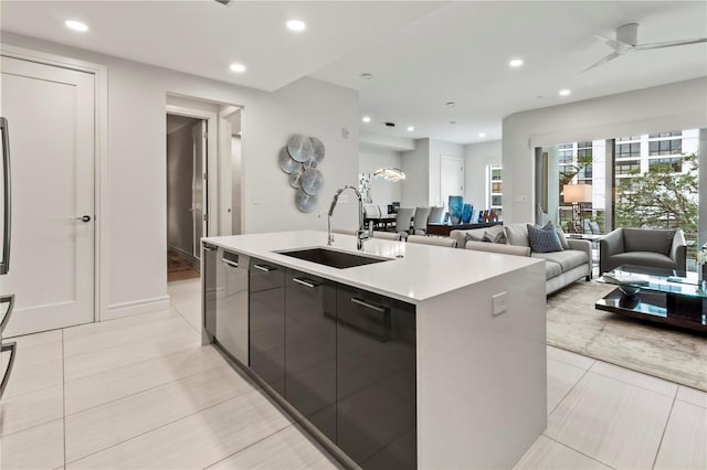 kitchen with light tile patterned flooring, sink, a center island with sink, stainless steel dishwasher, and ceiling fan