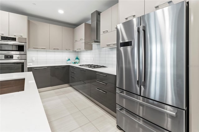 kitchen featuring wall chimney range hood, white cabinetry, backsplash, stainless steel appliances, and light tile patterned flooring