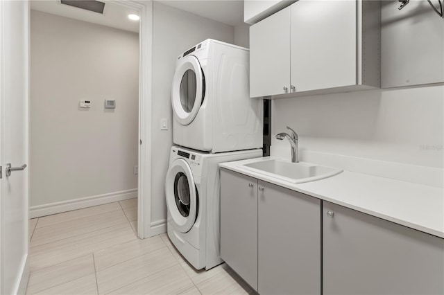 laundry room with cabinets, stacked washer and dryer, and sink