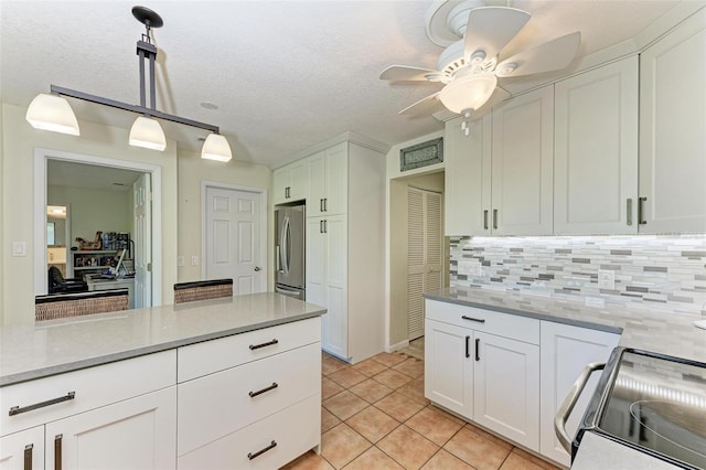 kitchen with appliances with stainless steel finishes, white cabinetry, hanging light fixtures, and backsplash