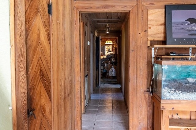 corridor with dark tile patterned flooring and wooden walls