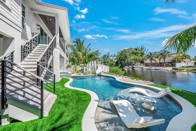 view of pool featuring a water view, a yard, a water slide, and a hot tub