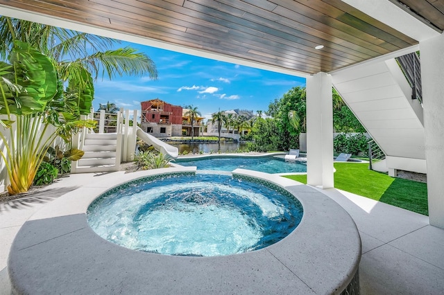 view of swimming pool featuring an in ground hot tub, a patio, a water view, and a water slide