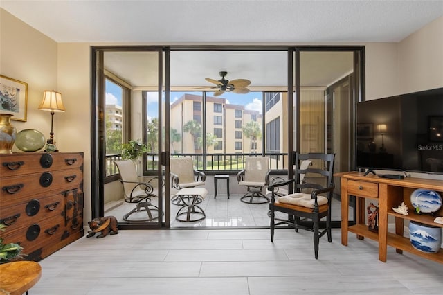 sitting room featuring ceiling fan and a wall of windows