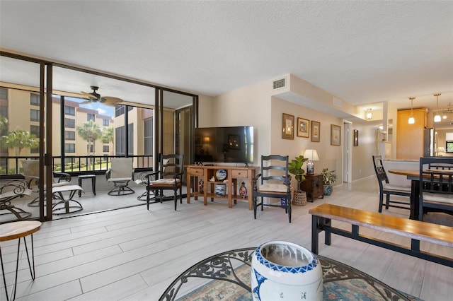 living room featuring floor to ceiling windows, ceiling fan, light hardwood / wood-style flooring, and a textured ceiling