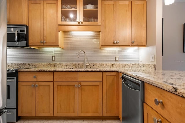 kitchen featuring backsplash, light stone countertops, sink, and appliances with stainless steel finishes