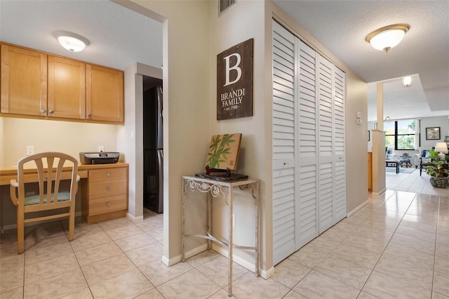 kitchen with black fridge, light tile patterned floors, and a textured ceiling