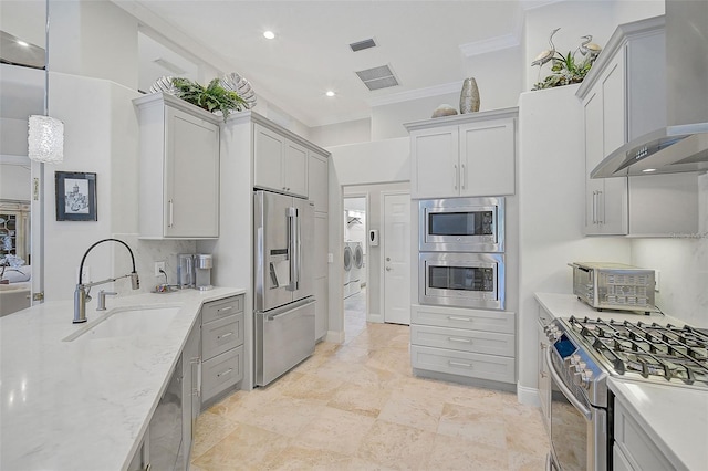 kitchen featuring hanging light fixtures, sink, wall chimney exhaust hood, appliances with stainless steel finishes, and light stone counters