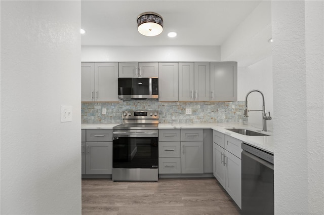 kitchen with light countertops, appliances with stainless steel finishes, gray cabinets, and a sink