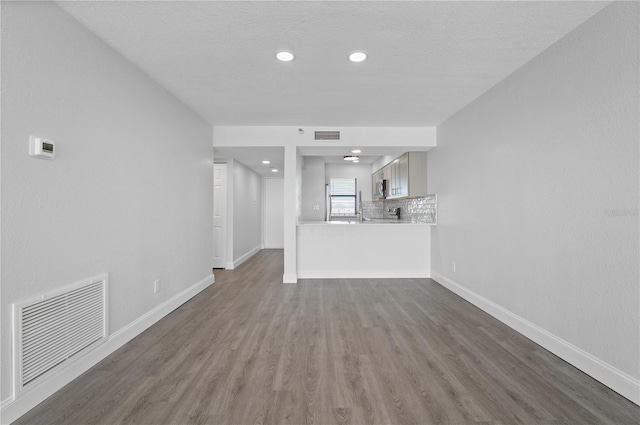 unfurnished living room featuring dark wood-style floors, visible vents, and baseboards