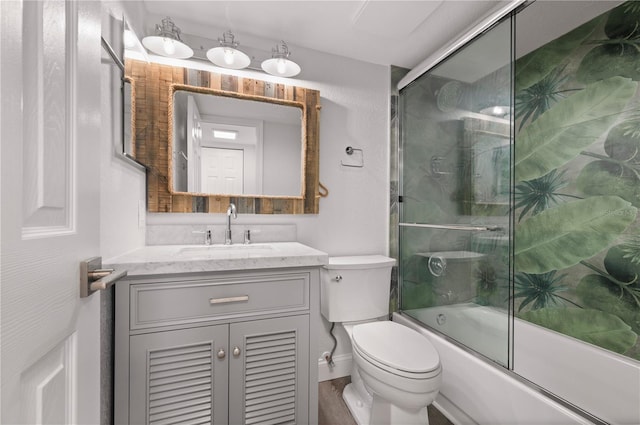 full bathroom featuring shower / bath combination with glass door, vanity, and toilet