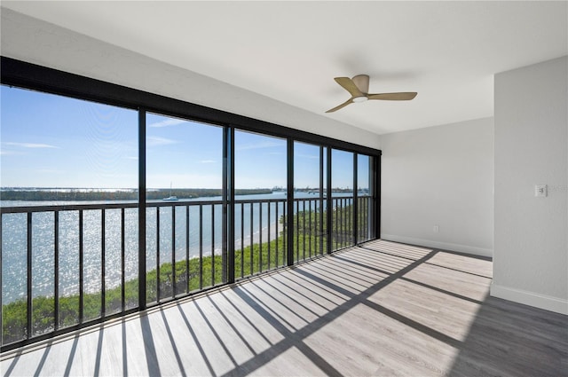 unfurnished sunroom with a water view and a ceiling fan