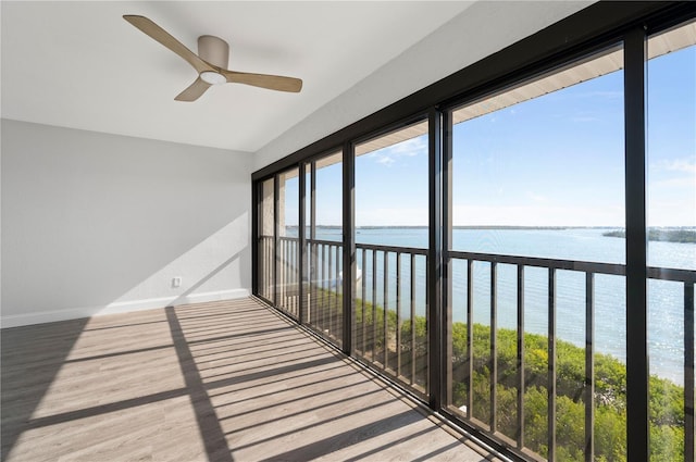 unfurnished sunroom with a water view and a ceiling fan