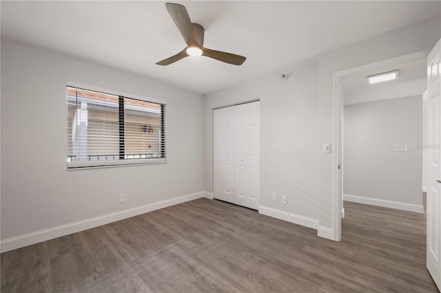 unfurnished bedroom featuring ceiling fan, baseboards, dark wood finished floors, and a closet