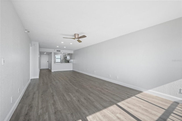 unfurnished living room with ceiling fan, wood finished floors, and baseboards