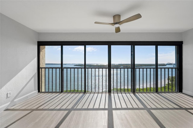 unfurnished sunroom featuring plenty of natural light, a water view, and a ceiling fan