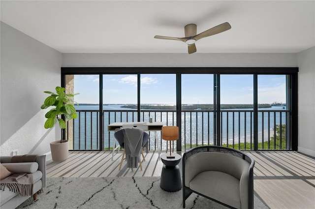 sunroom featuring a ceiling fan, a healthy amount of sunlight, and a water view