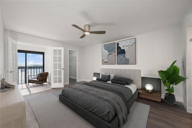 bedroom featuring french doors, dark wood finished floors, a water view, access to outside, and baseboards