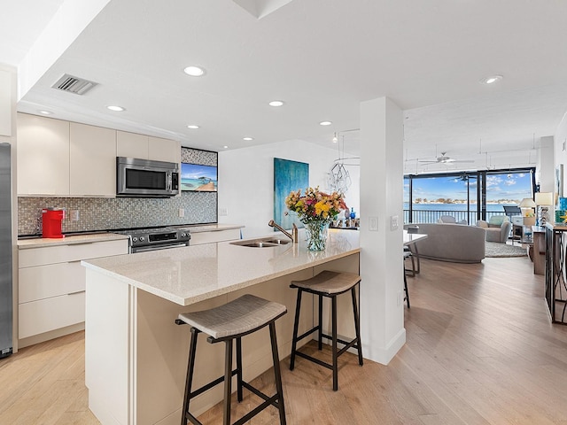 kitchen with white cabinets, a kitchen breakfast bar, sink, and stainless steel appliances