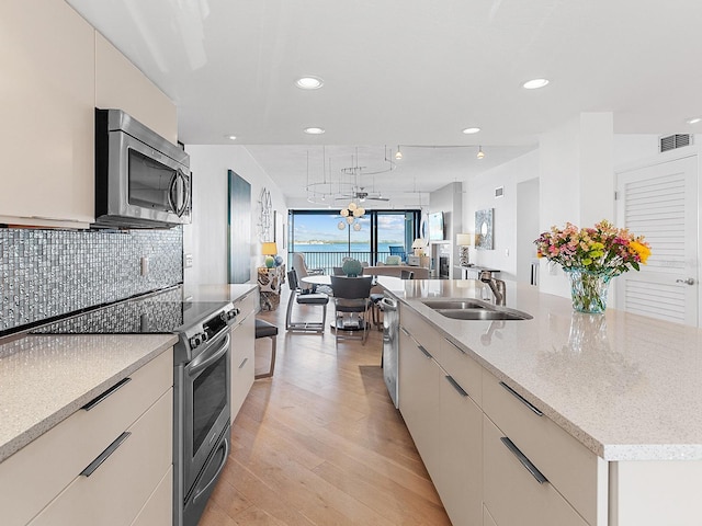 kitchen featuring a spacious island, sink, ceiling fan, light wood-type flooring, and appliances with stainless steel finishes