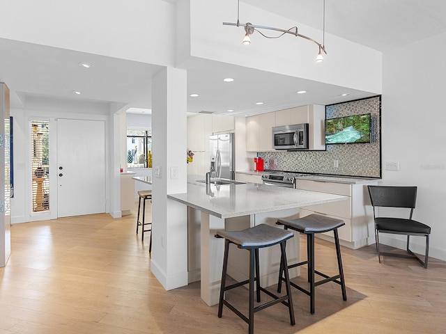 kitchen with a breakfast bar area, white cabinetry, hanging light fixtures, and appliances with stainless steel finishes