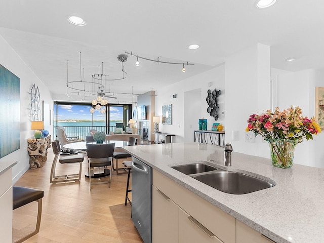 kitchen featuring light stone counters, sink, stainless steel dishwasher, and light hardwood / wood-style floors