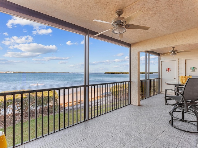 sunroom / solarium with a beach view, a water view, and ceiling fan