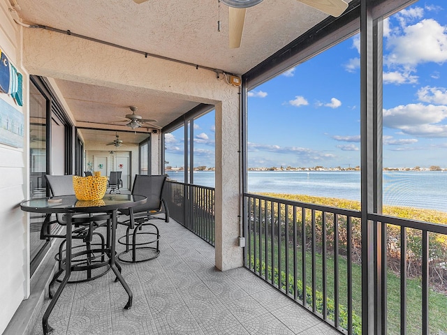 sunroom / solarium featuring ceiling fan and a water view