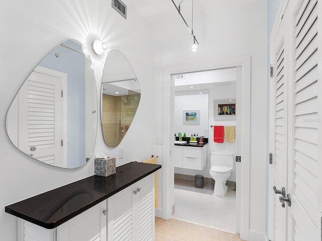 bathroom featuring tile patterned floors, vanity, toilet, and rail lighting