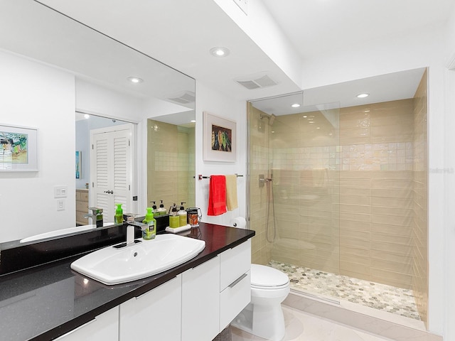 bathroom featuring a tile shower, vanity, and toilet