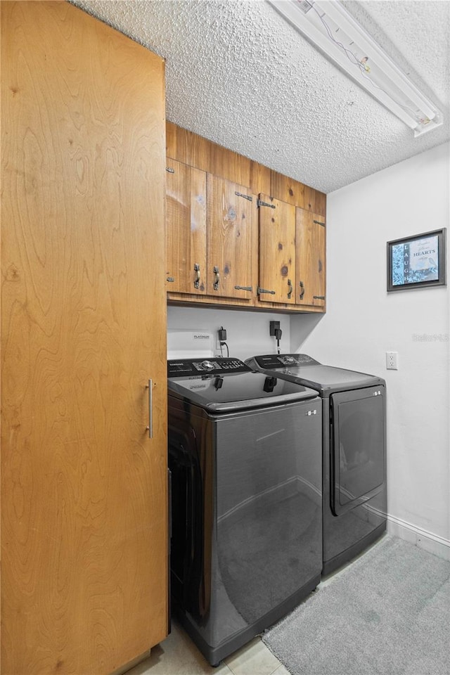 clothes washing area featuring cabinets, washing machine and dryer, and a textured ceiling