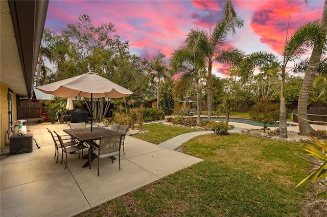 patio terrace at dusk featuring a yard