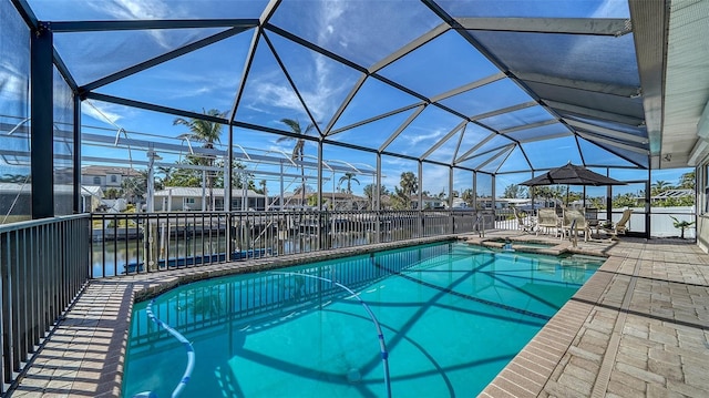 view of pool with a patio area, an in ground hot tub, glass enclosure, and a water view