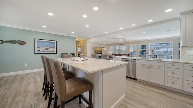 kitchen featuring a kitchen bar, dishwasher, sink, and white cabinets