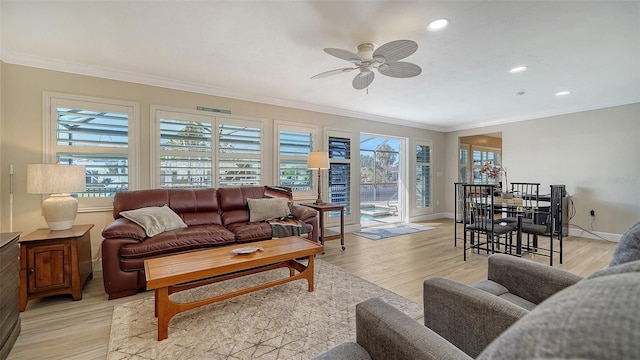 living room with crown molding, a wealth of natural light, and light wood-type flooring