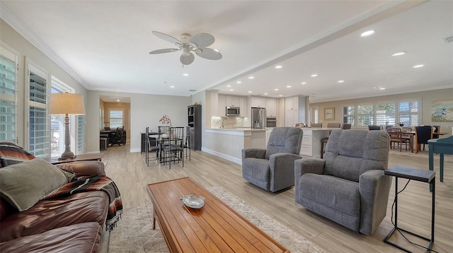 living room featuring ornamental molding, ceiling fan, and light wood-type flooring