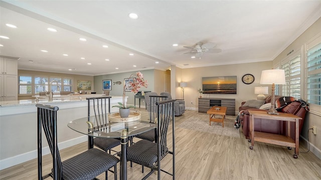 dining room with ceiling fan, ornamental molding, and light hardwood / wood-style flooring