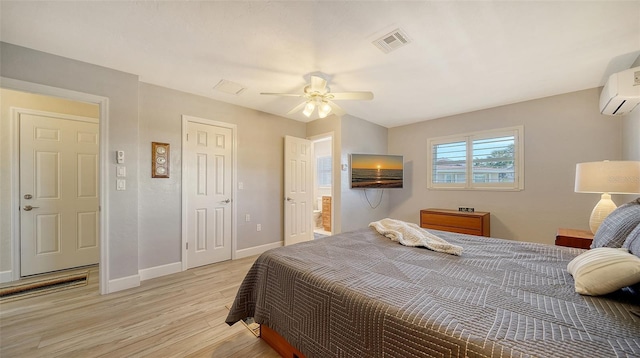 bedroom with ceiling fan, a wall unit AC, and light hardwood / wood-style floors