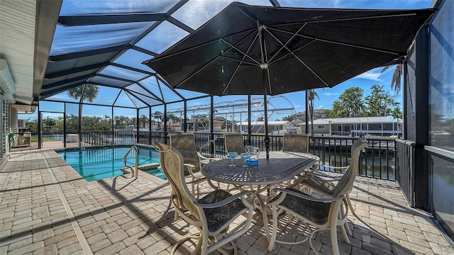 view of pool with a water view, a patio, and glass enclosure